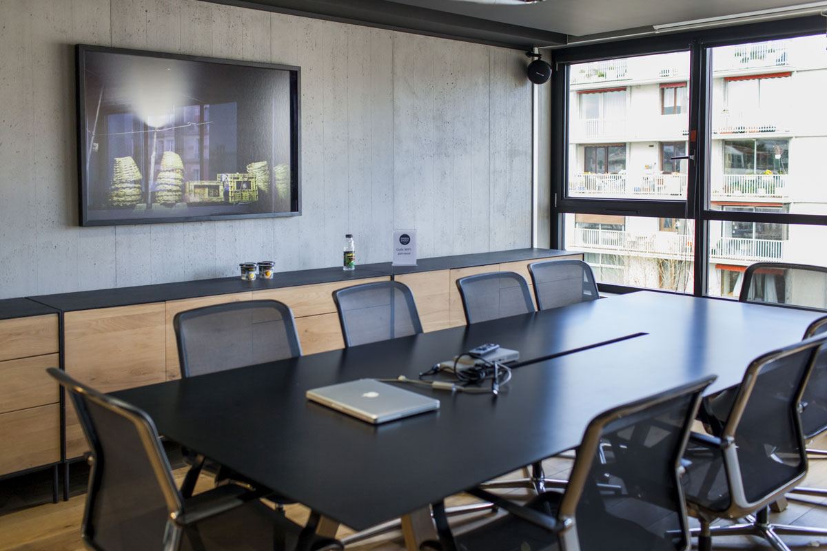 Salle de réunion Urban Food : grande table noire, murs en béton ciré et bahut en chêne