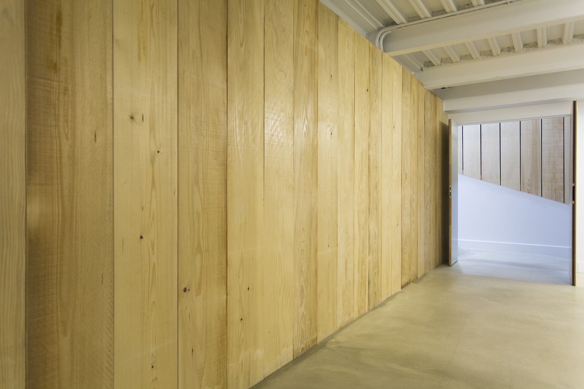 Circulation habillée d'un bardage bois clair sur sol béton ciré, bureaux Veepee