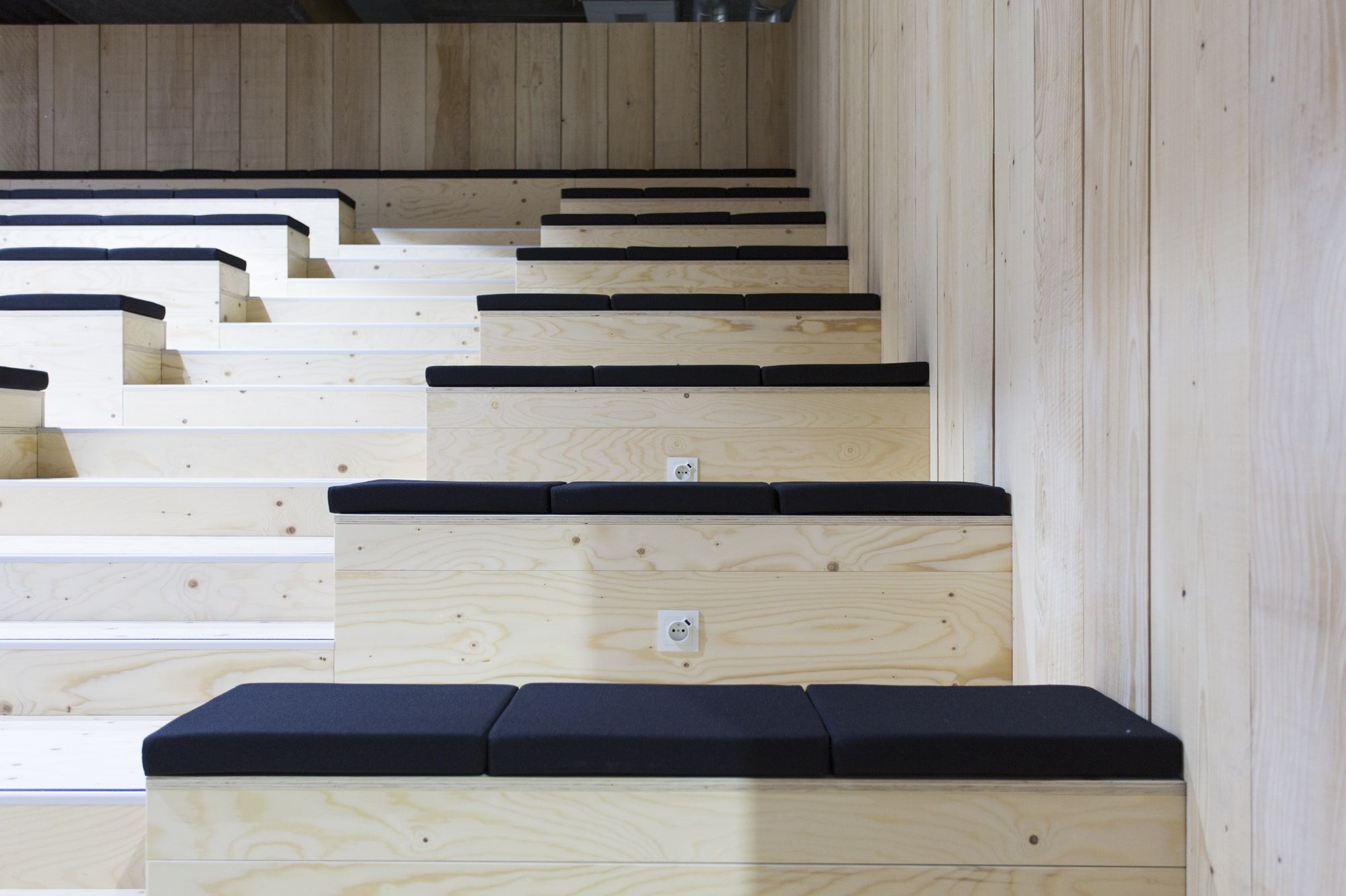 Détail des gradins en bois clair avec prises intégrées, amphithéâtre Veepee