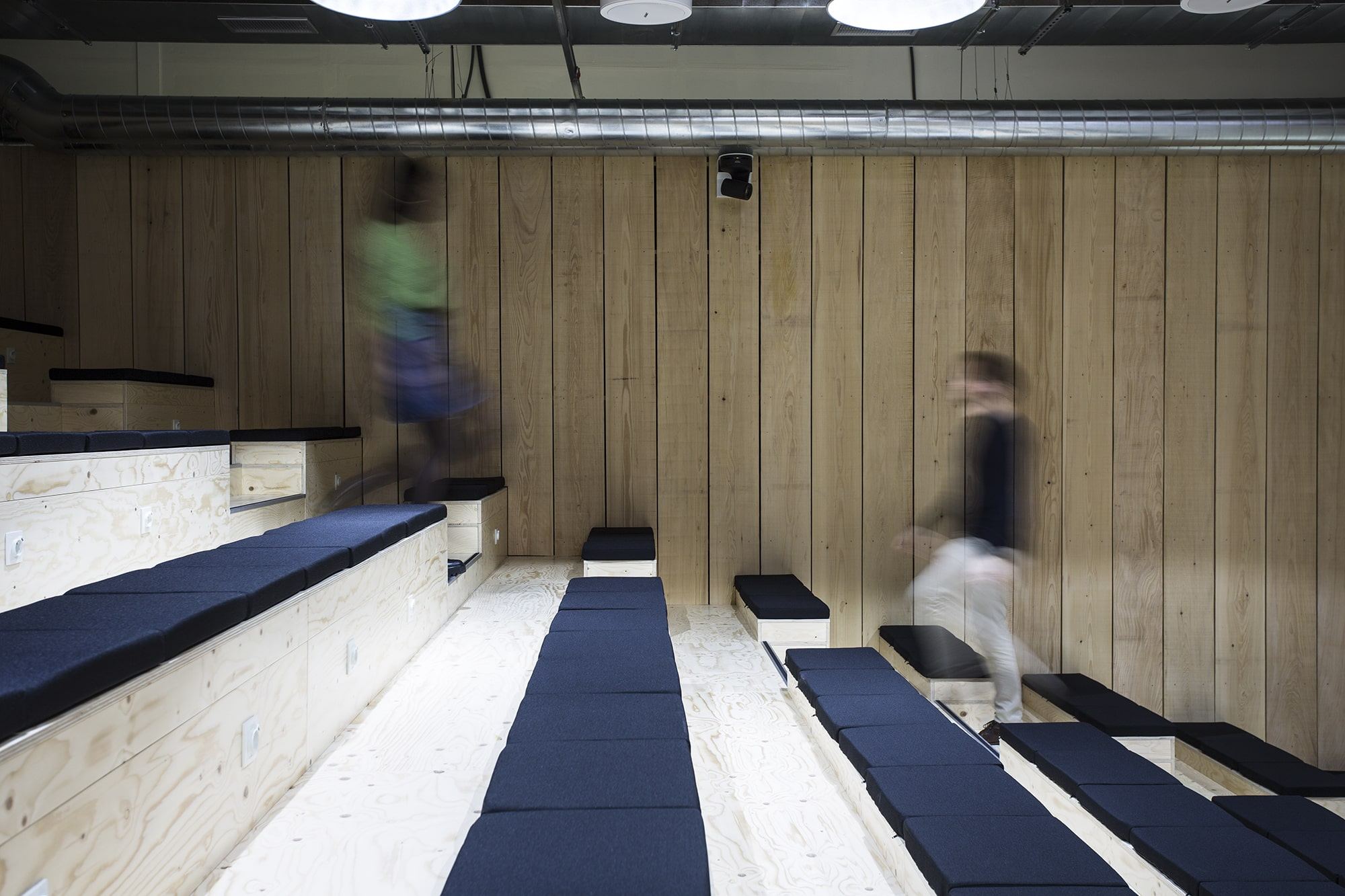 Gradins de l'amphithéâtre Veepee avec assises bleu marine et bardage bois