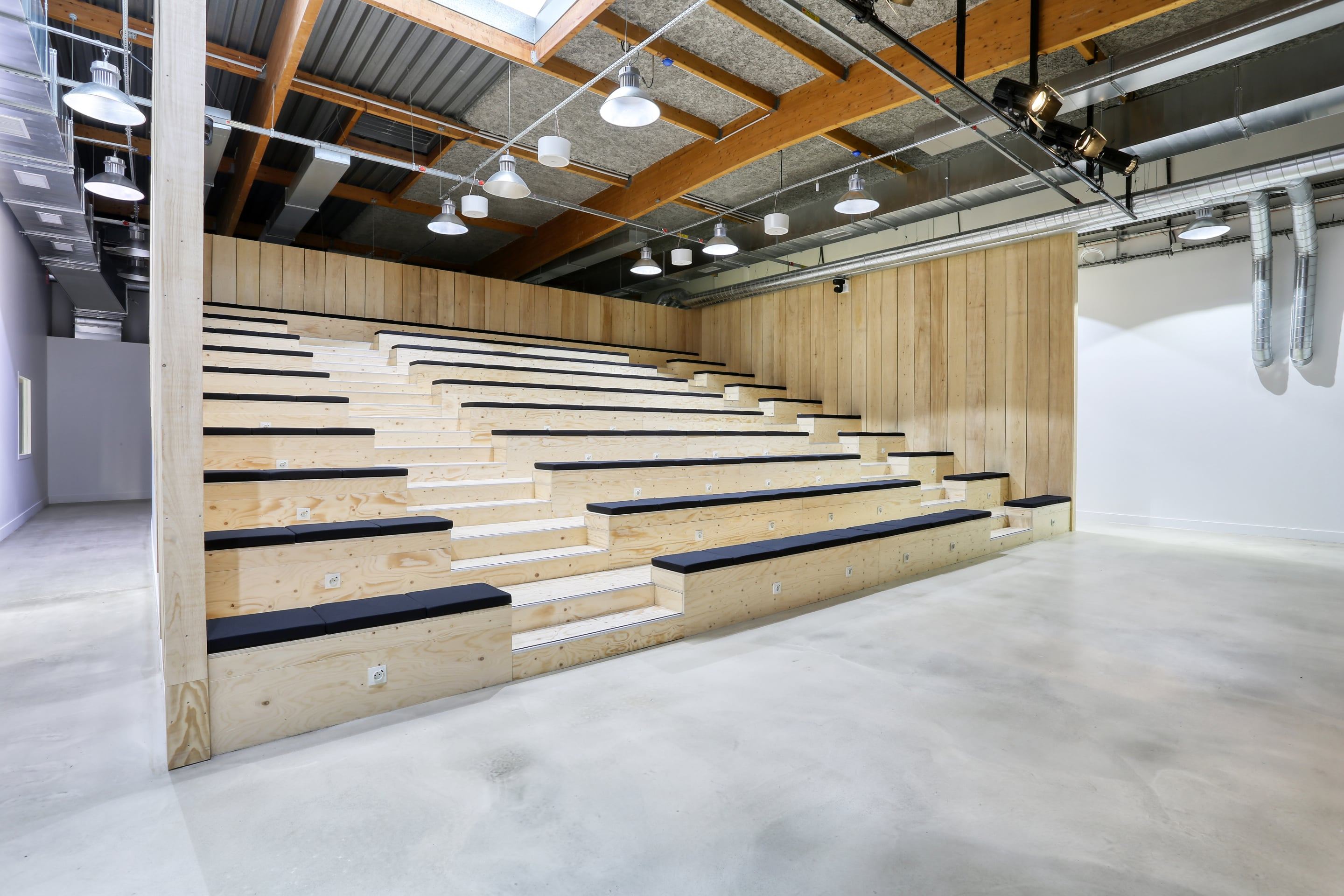 Amphithéâtre aux gradins en bois clair des bureaux Veepee Le Pressensé à Saint-Denis, aménagé par Isospace