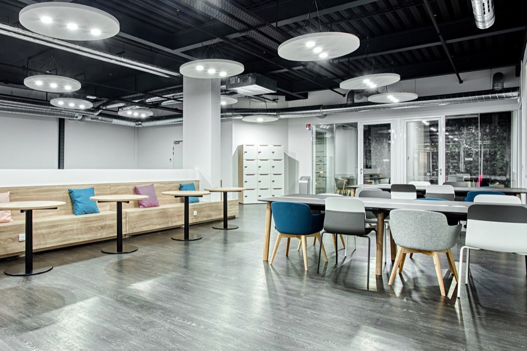 Suspensions acoustiques rondes sous plafond béton noir dans l’espace de coworking Veepee