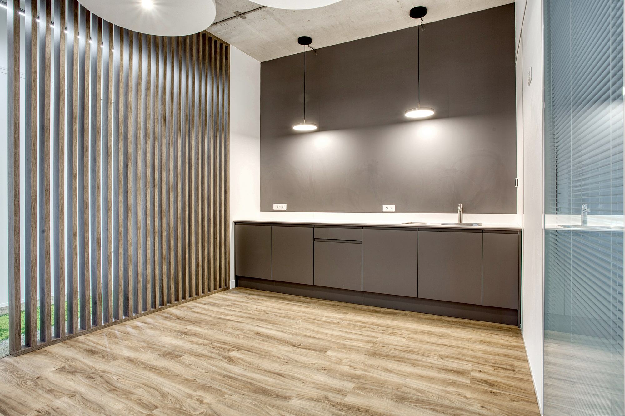 Cuisine d’entreprise Antemeta aménagée par Isospace : claustra en bois, plan de travail design et tabourets hauts