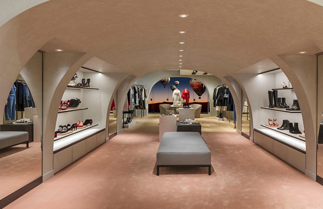 Perspective sous arches de la boutique Dior à Bruxelles avec podiums et présentoirs