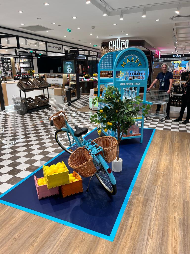 Vélo Malfy chargé de paniers et citronnier devant le présentoir, espace duty-free
