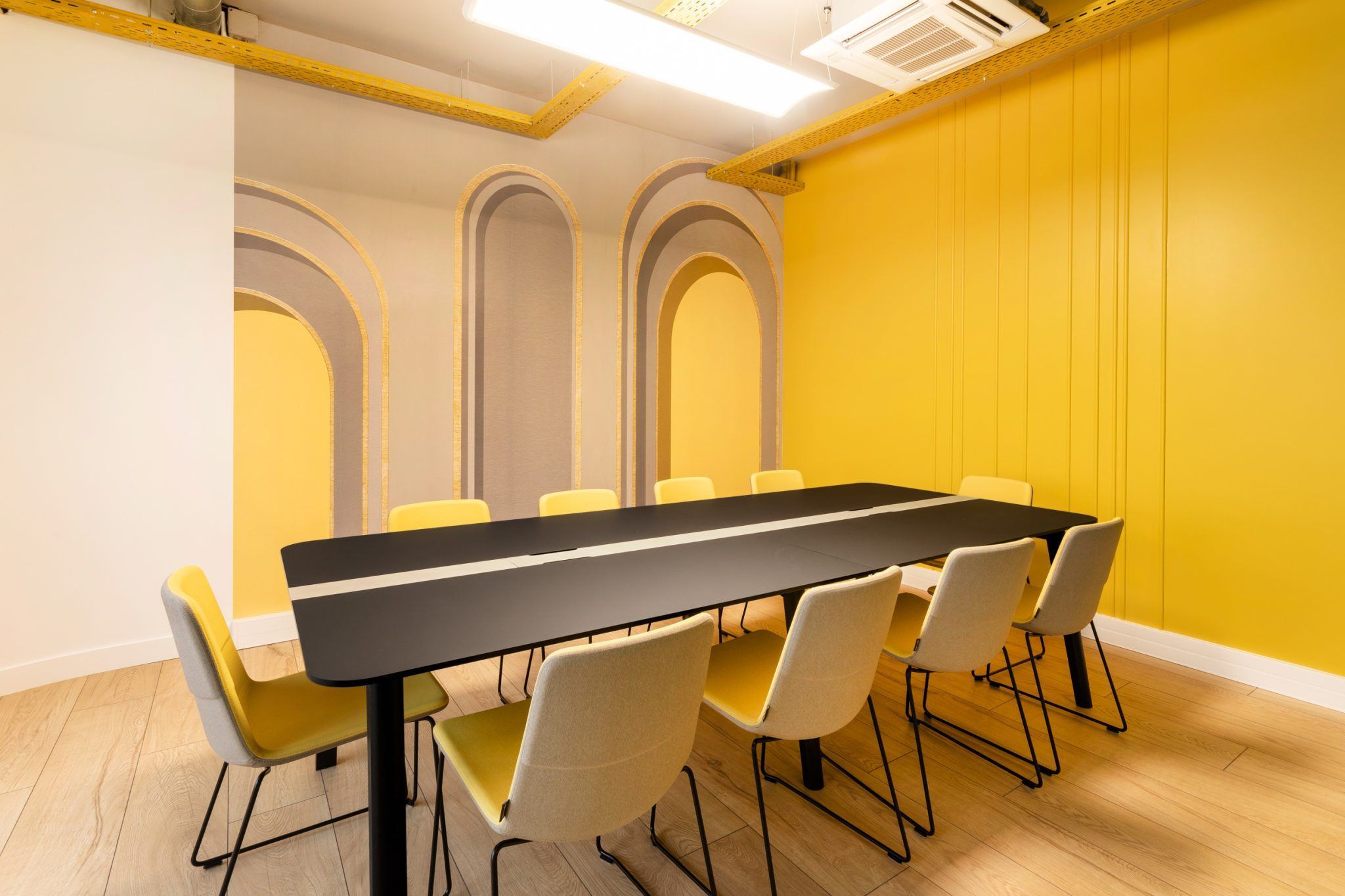 Salle de réunion à grande table noire et chaises colorées, siège Scaleway aménagé par Isospace