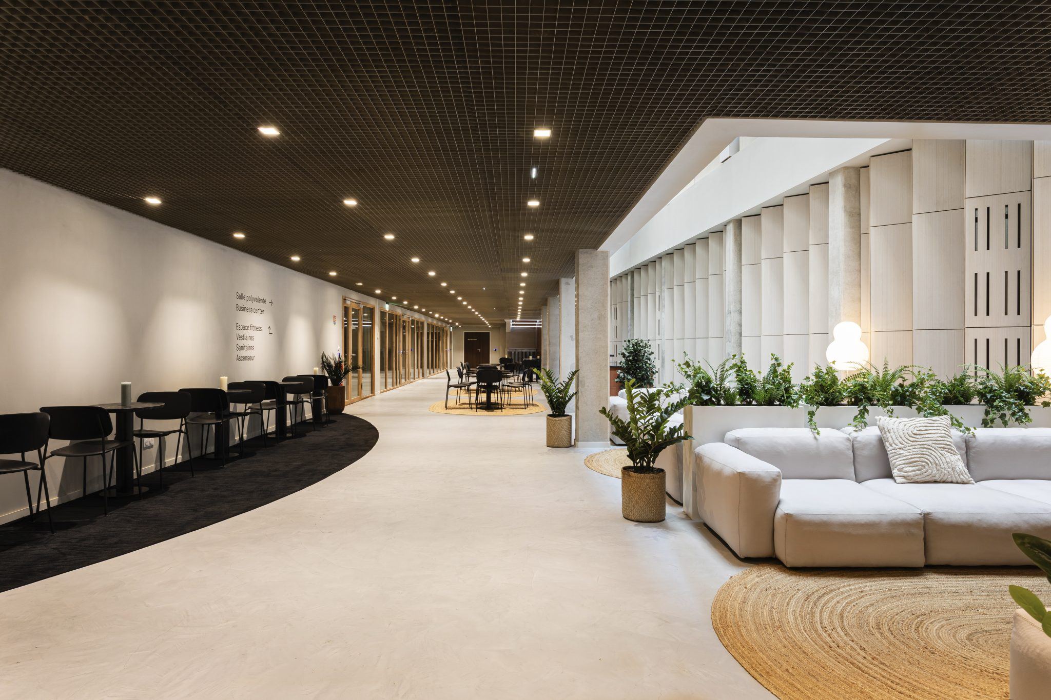 Grande circulation de bureaux avec assises lounge et coins de travail aménagés par Isospace