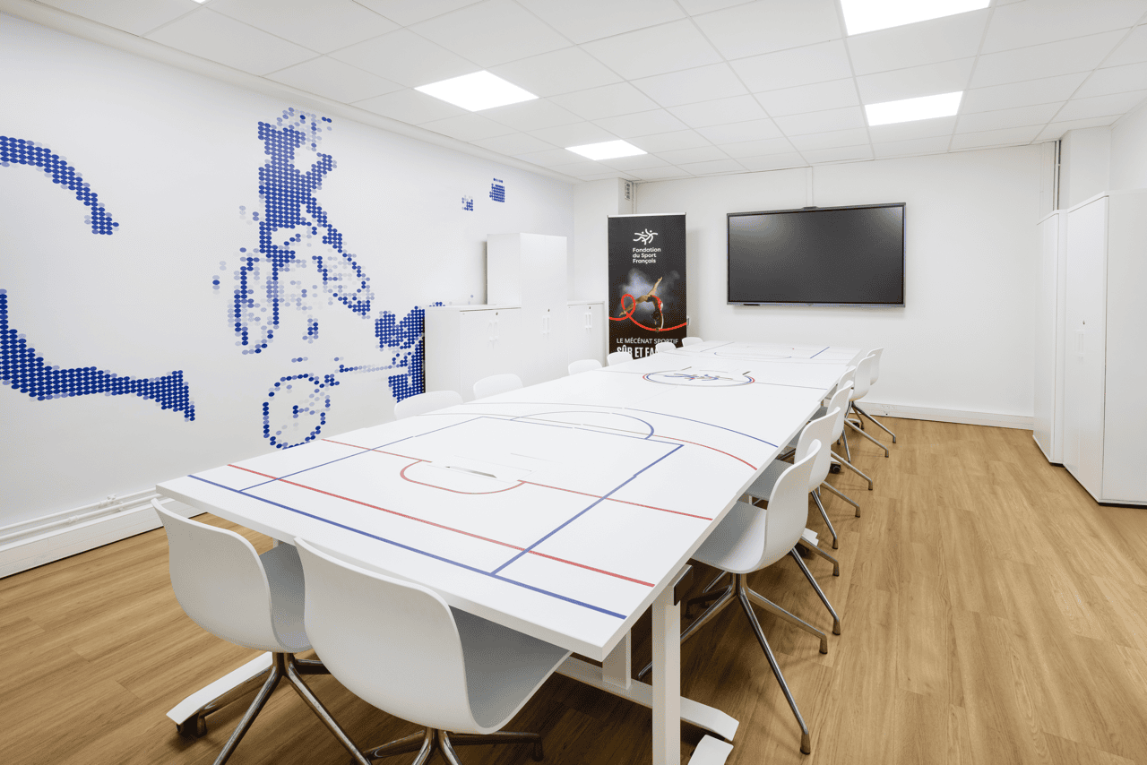 Salle de réunion avec table imprimée façon aire de jeu et écran