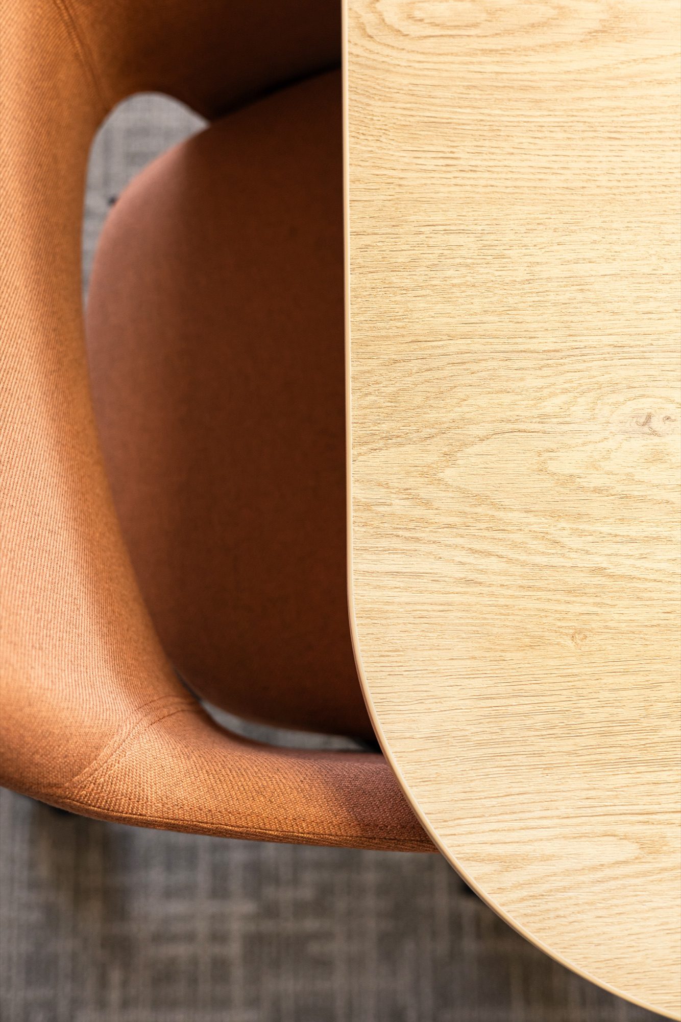 Détail d'un fauteuil terracotta et d'une table en bois clair, bureaux d'un laboratoire pharmaceutique