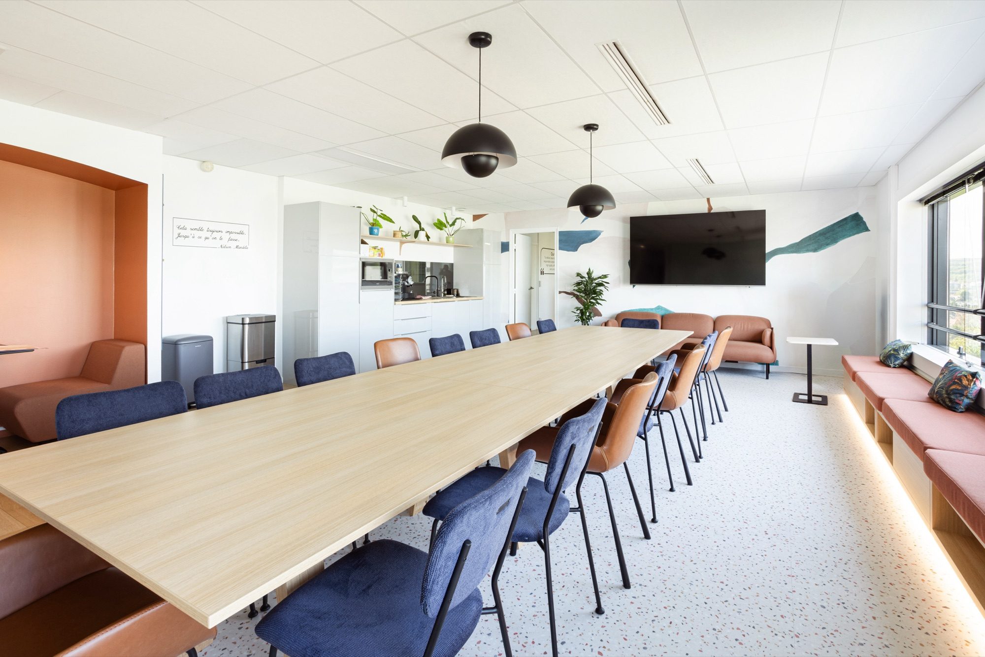 Espace de réunion convivial avec grande table et chaises colorées dans des bureaux pharmaceutiques