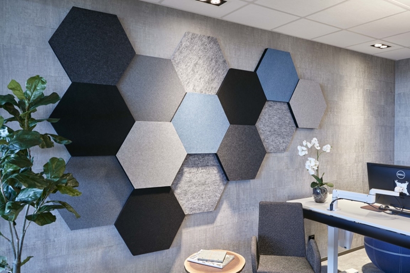 Panneau acoustique mural Honey EcoSUND, composition hexagonale dans les tons bleu et gris au-dessus d’un poste de travail