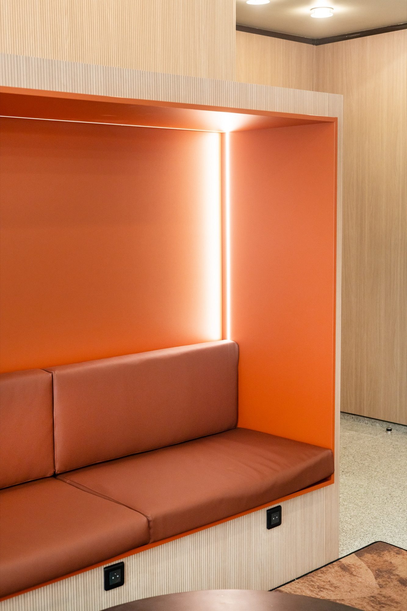 Alcôve à banquette orange et habillage en bois cannelé