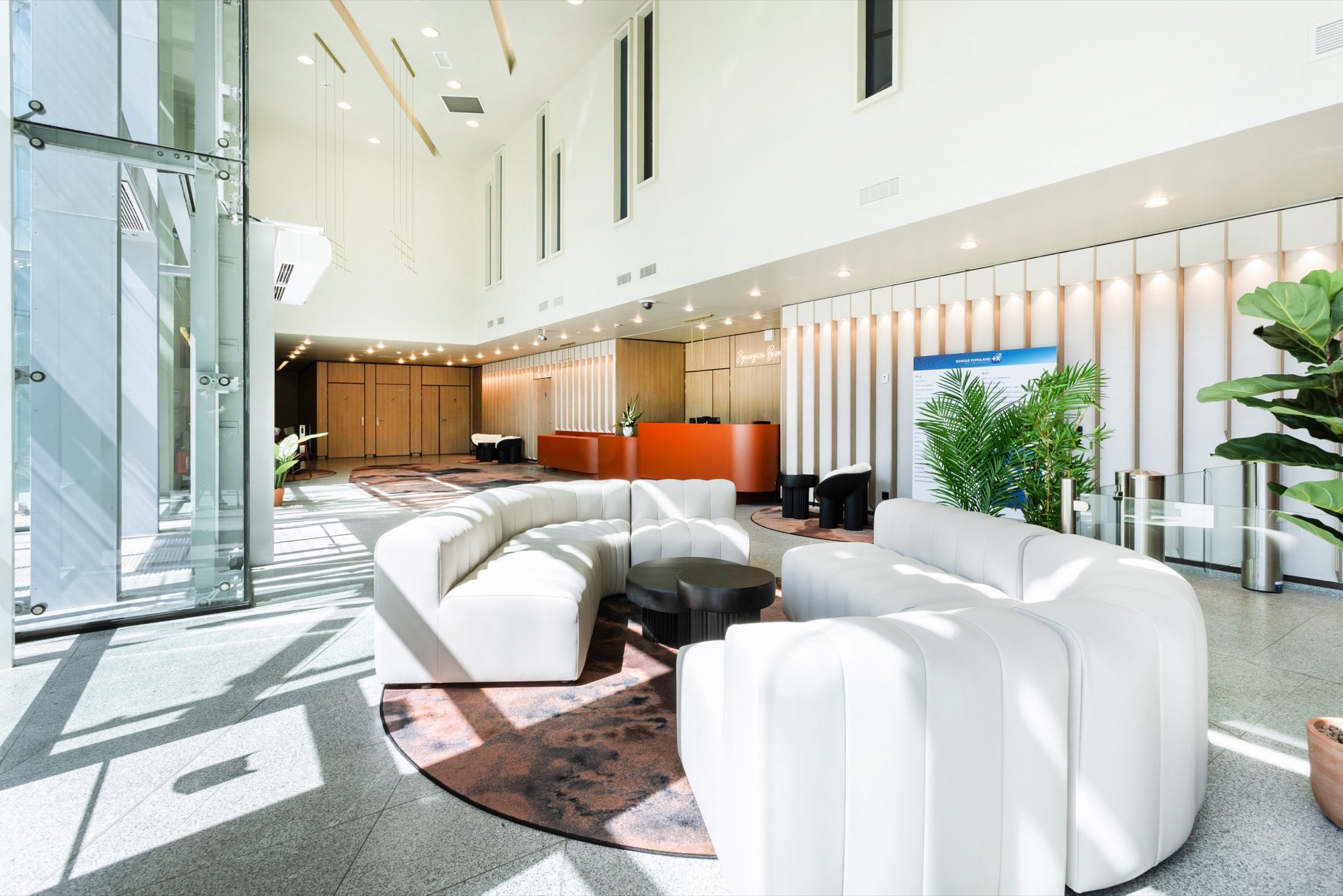 Hall d'accueil aux banquettes claires et tapis aux motifs organiques sur terrazzo