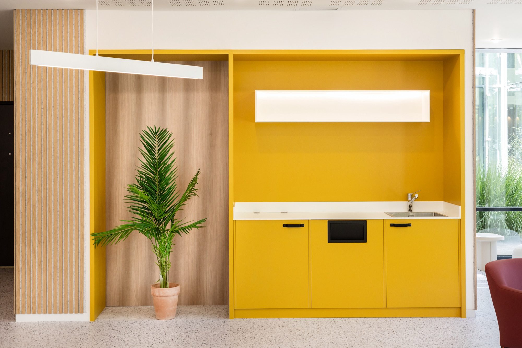 Kitchenette jaune à niche bois et suspension linéaire dans un salon
