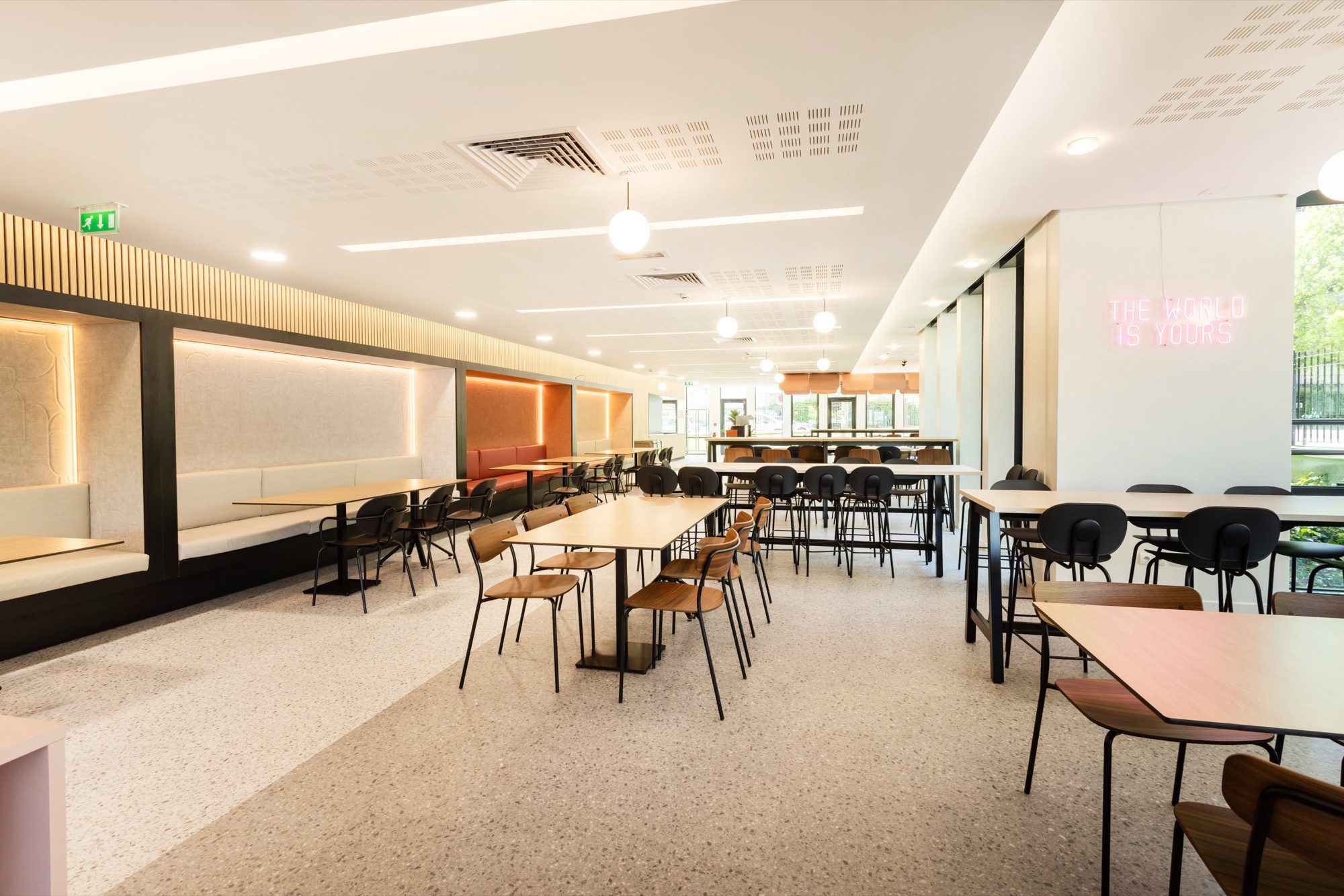 Cafétéria du RIE avec bar en bois, banquettes et enseigne néon décorative