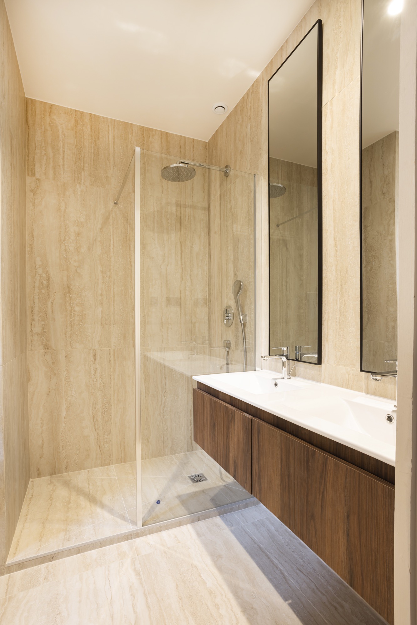 Salle d'eau habillée de travertin avec douche à l'italienne et meuble noyer