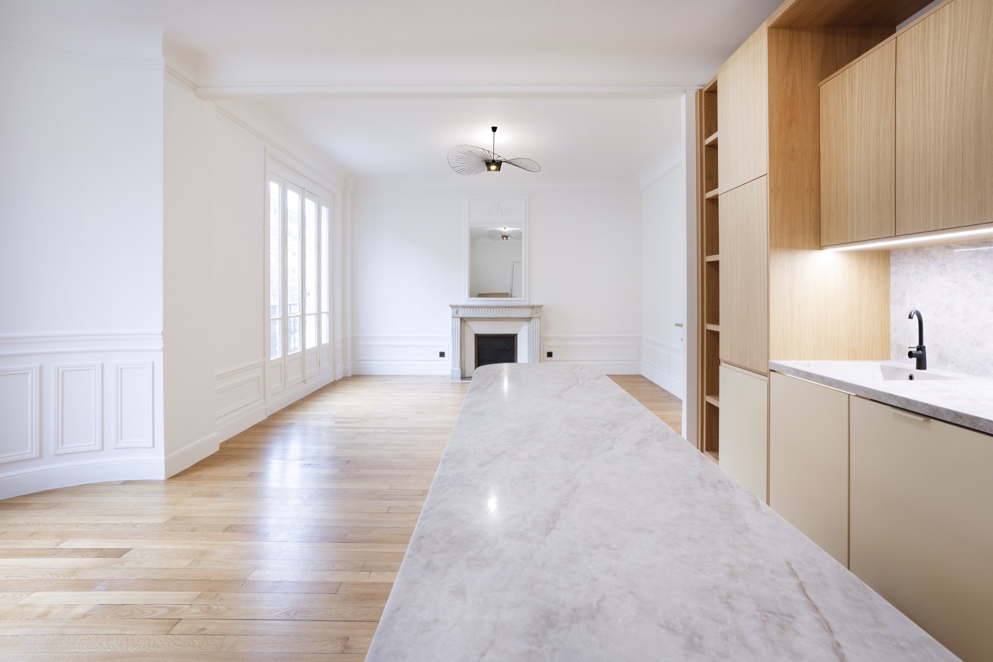 Séjour lumineux avec cheminée en marbre, îlot et parquet chêne restauré