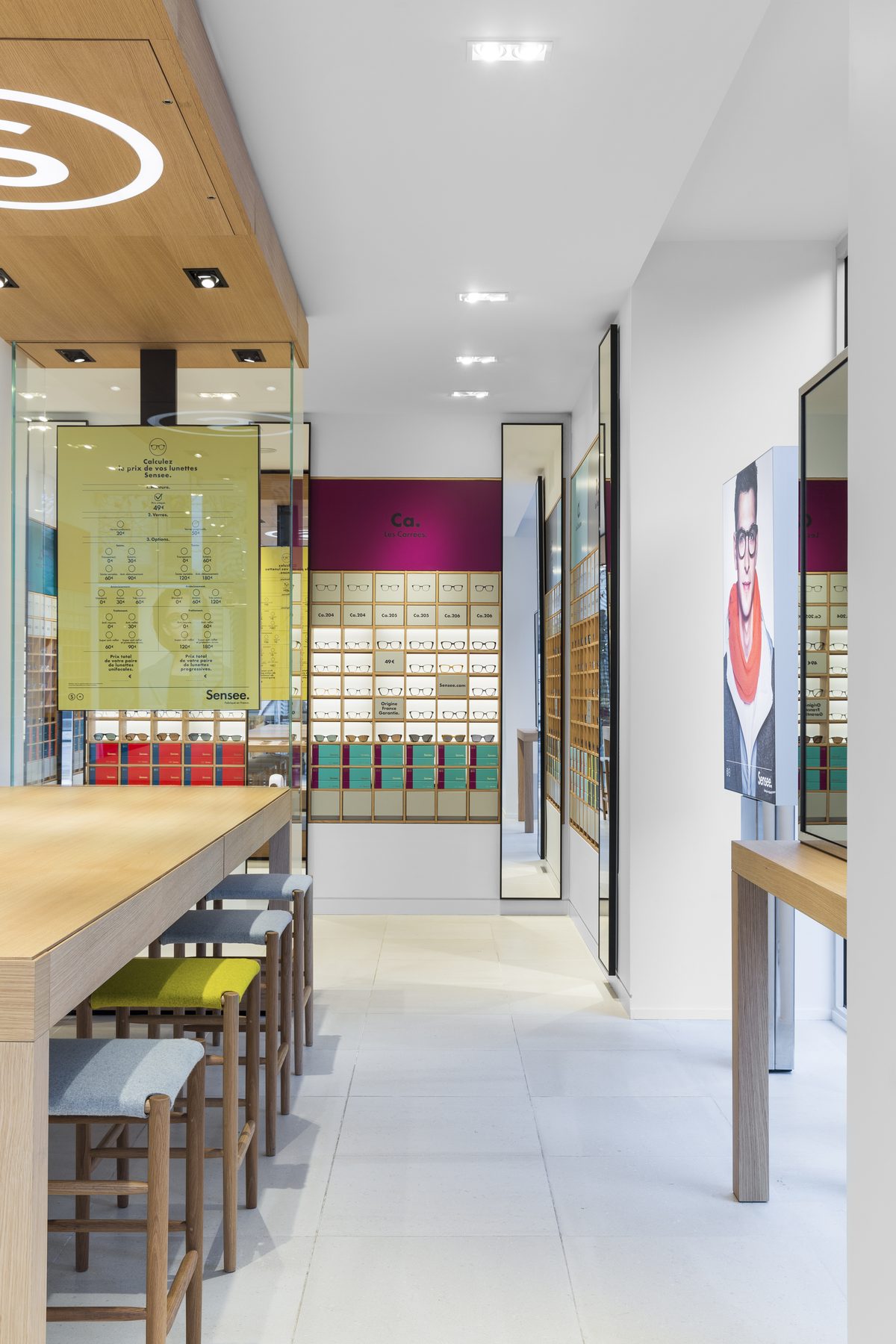Espace d’essayage avec tabourets bois et panneau graphique jaune