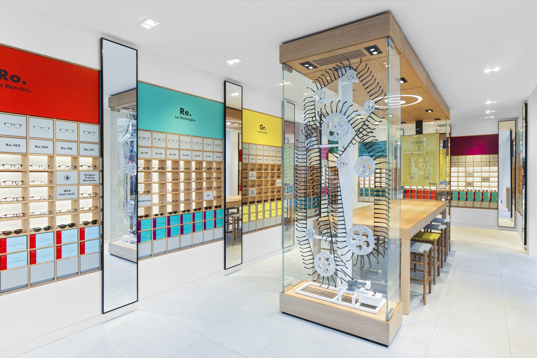 Vue d’ensemble de la boutique d’optique Sensee agencée par Isospace, murs de montures et vitrine centrale