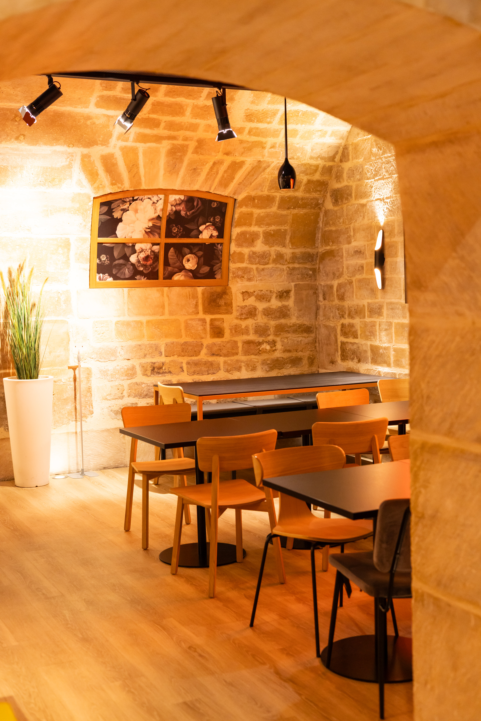 Salle voûtée en pierre apparente avec tables et éclairage sur rail, Agora
