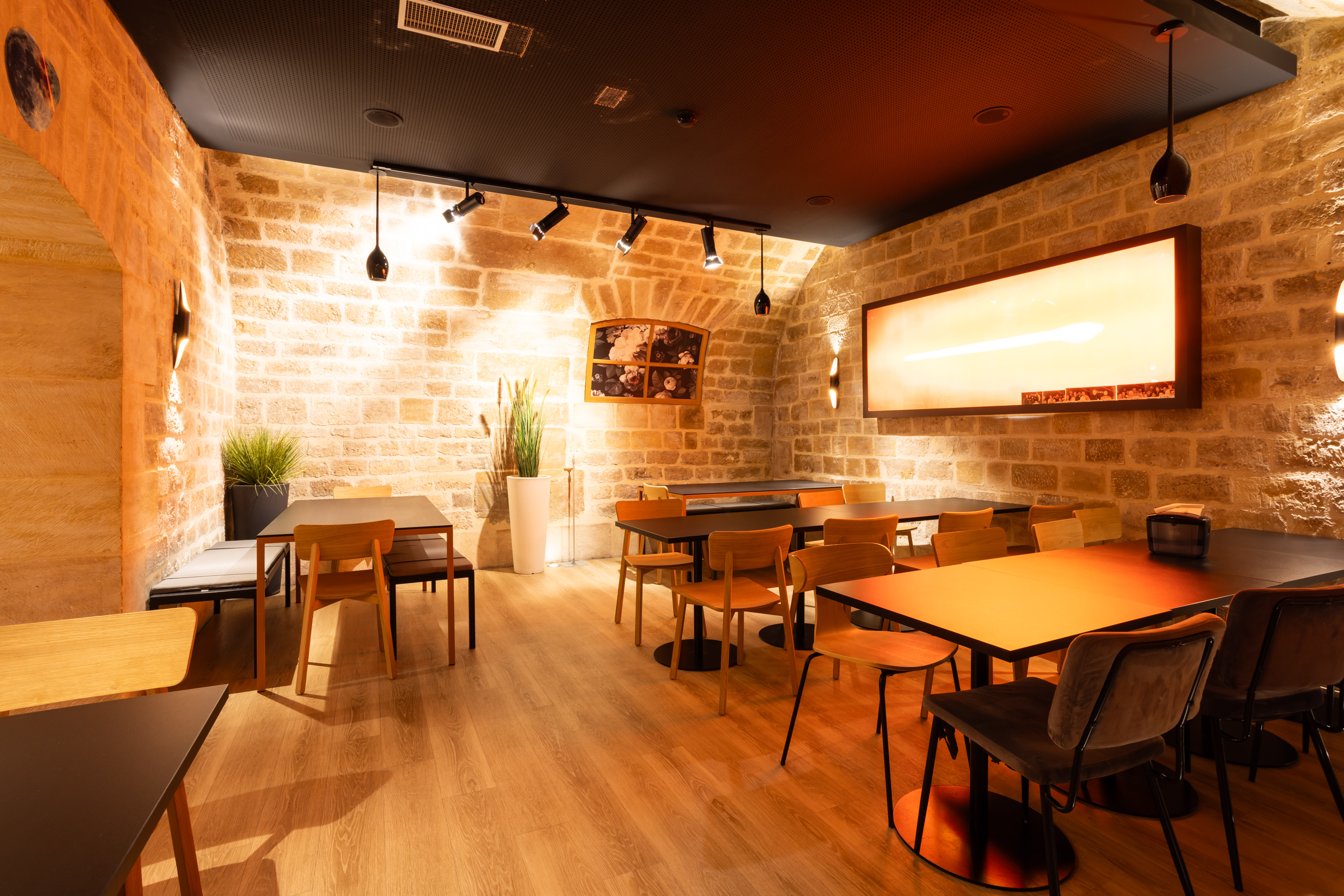Salle voûtée en pierre de taille avec tables et banquettes, espace de restauration Agora