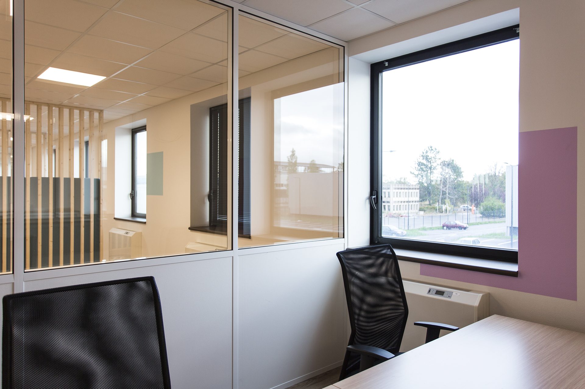 Bureau individuel vitré avec vue extérieure et mur rose