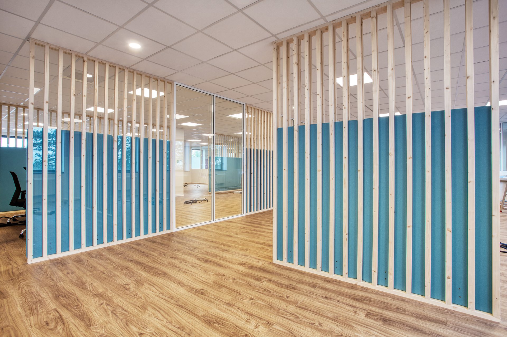 Perspective de couloir bordé de claustras bois et panneaux acoustiques, bureaux en flex office
