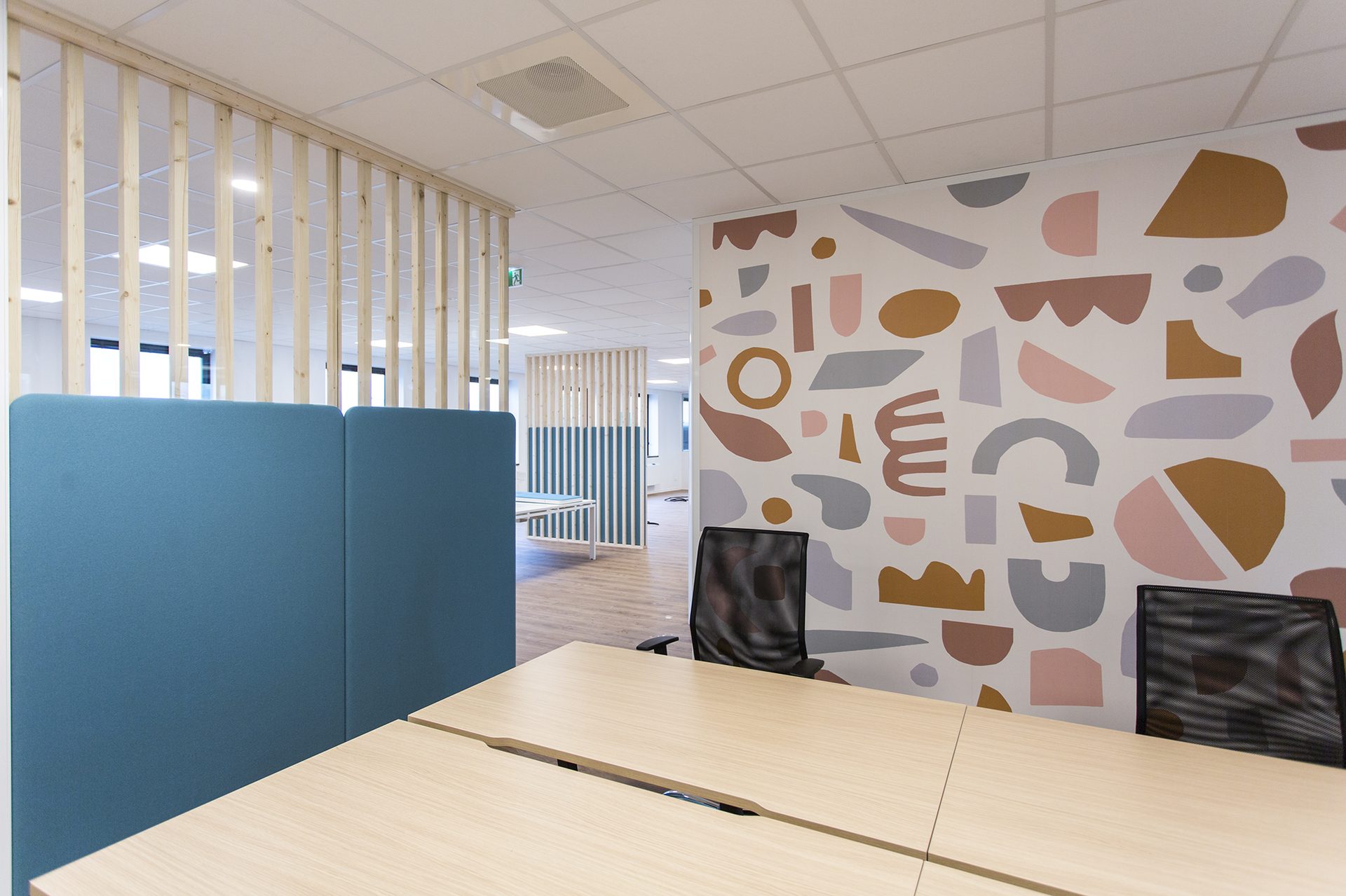 Cloison acoustique bleue et fresque graphique terracotta dans l'open space