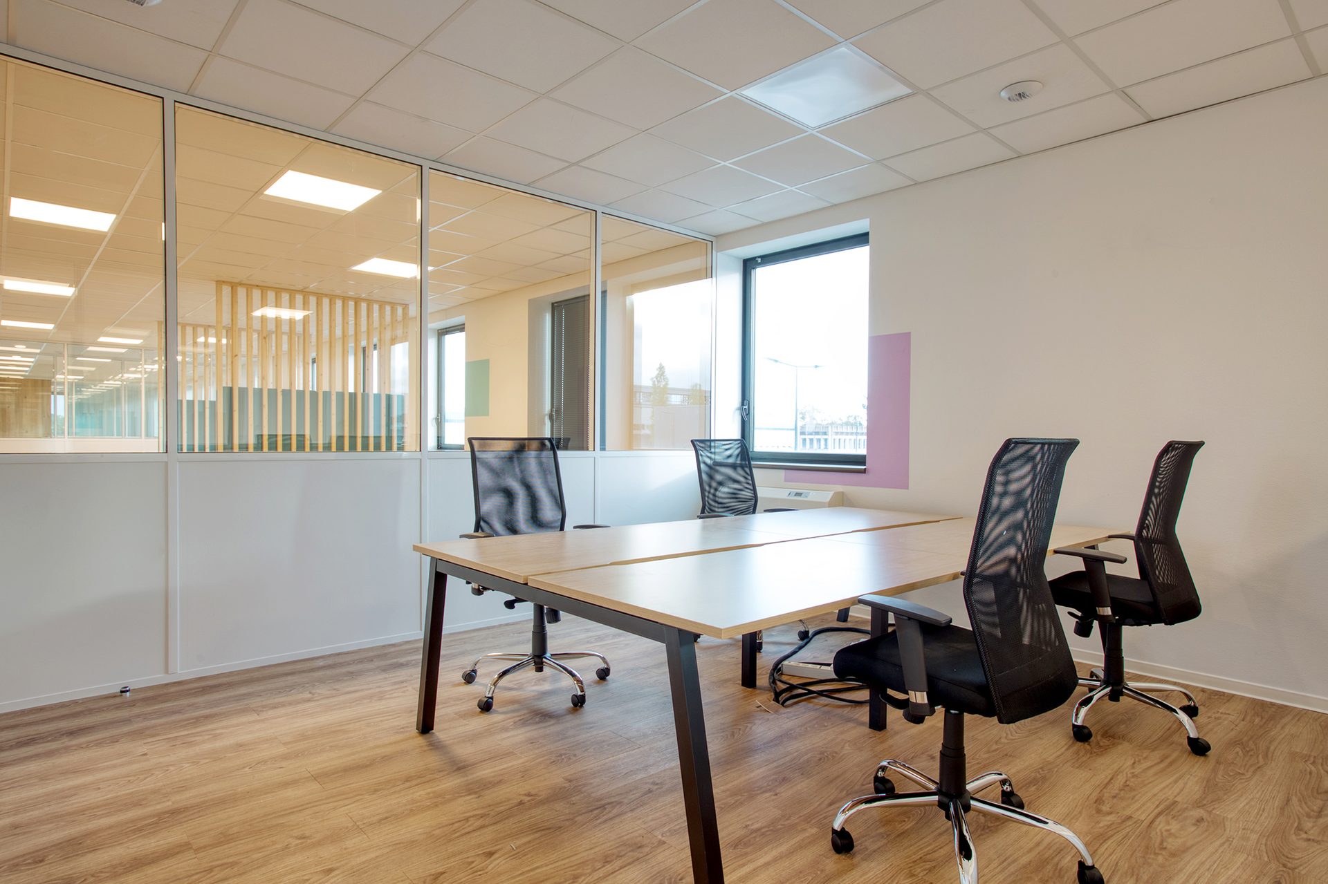 Open space en flex office avec cloisons vitrées et postes de travail sur sol bois