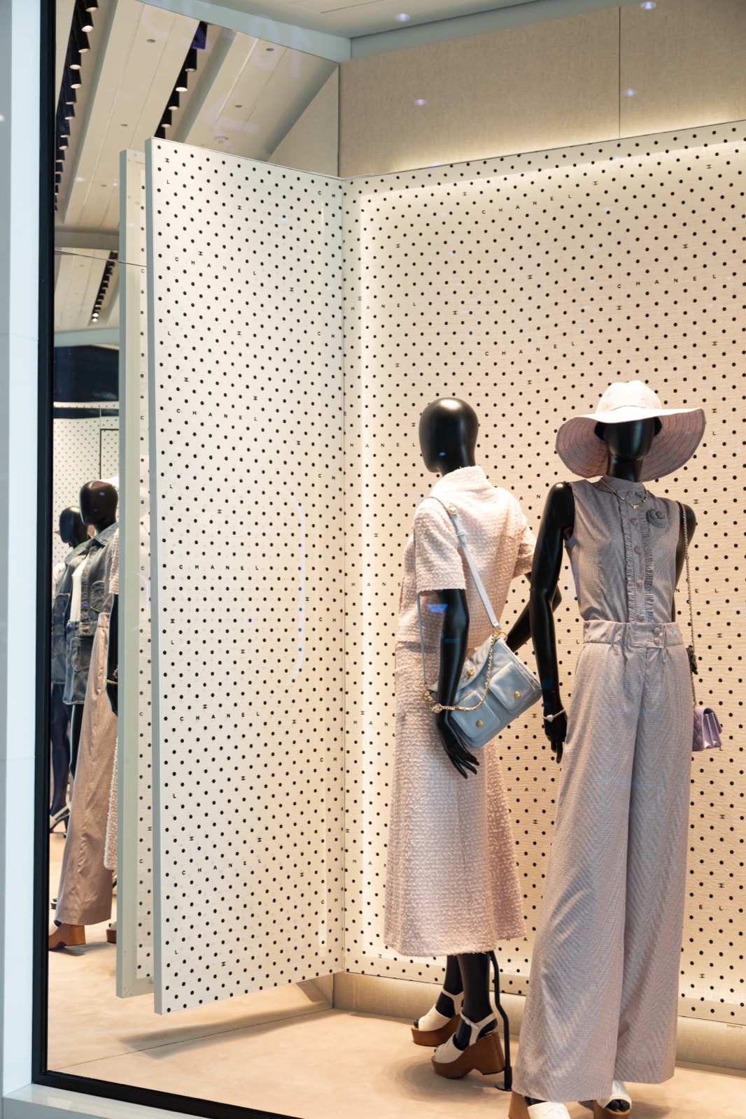Mannequins Chanel en chapeaux devant la façade perforée