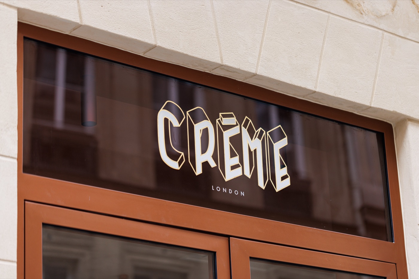Lettrage doré sur la vitrine de la boutique Crème London par Isospace