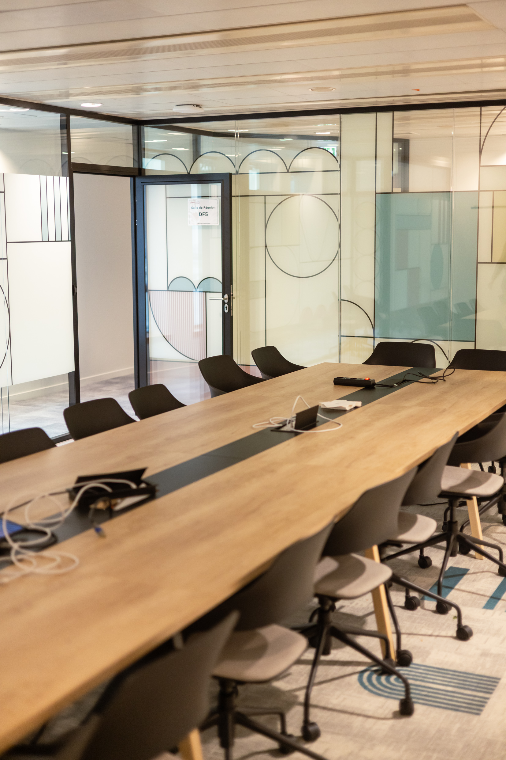 Salle de réunion fermée par des cloisons vitrées à décor graphique circulaire