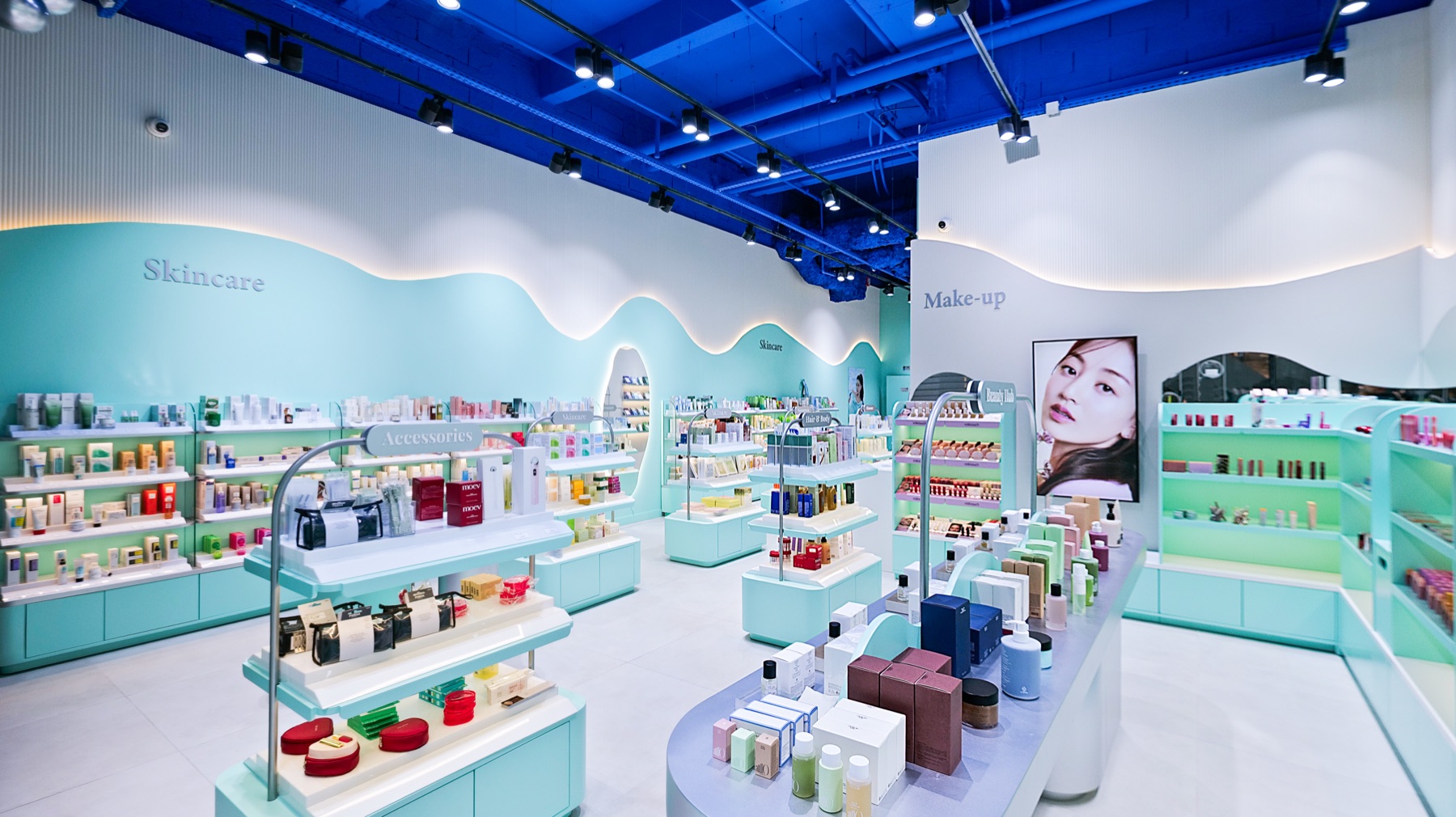 Murs skincare et make-up de la boutique Joo Beauty, meubles laqués vert d'eau et étagères éclairées