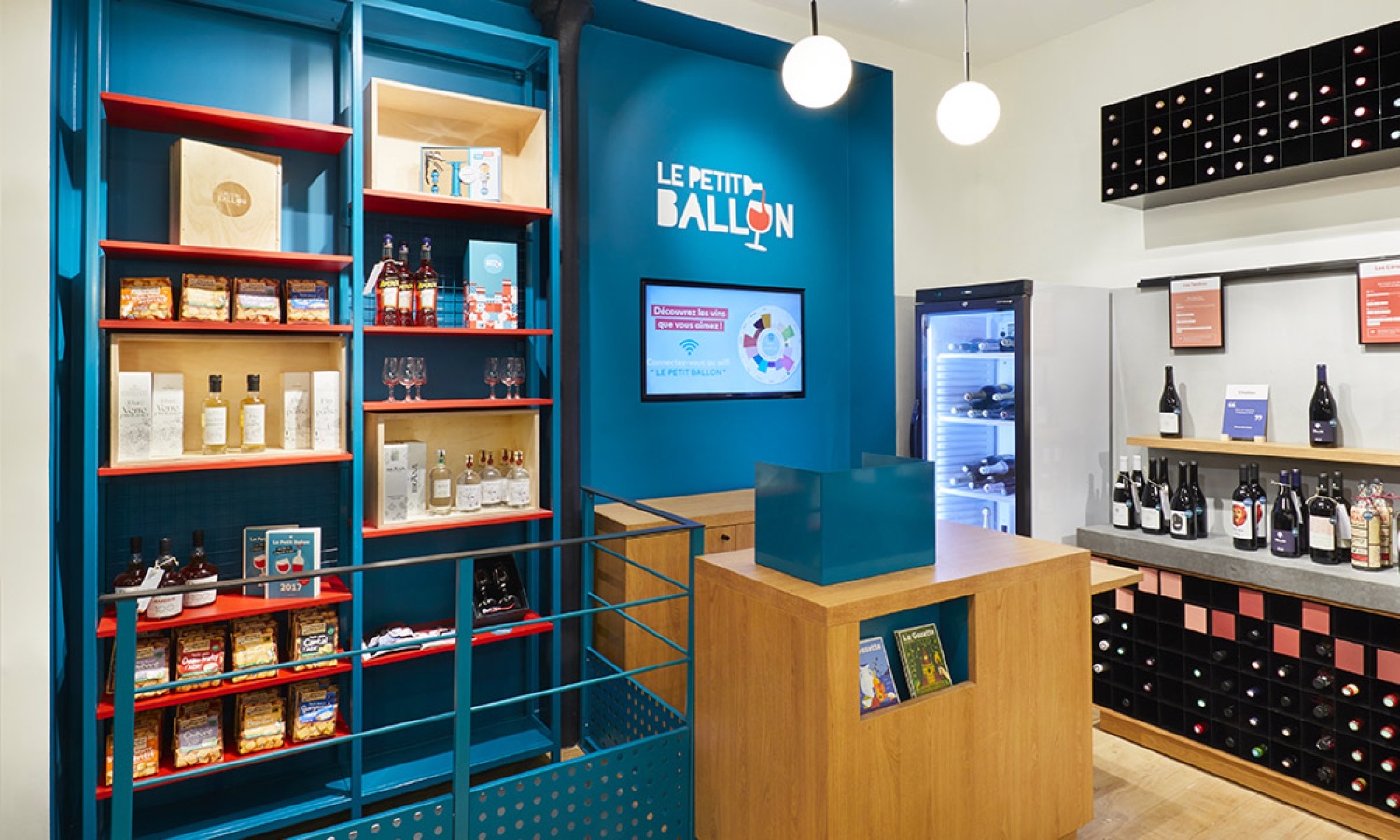 Étagères bleu et rouge et logo Le Petit Ballon dans la boutique agencée par Isospace
