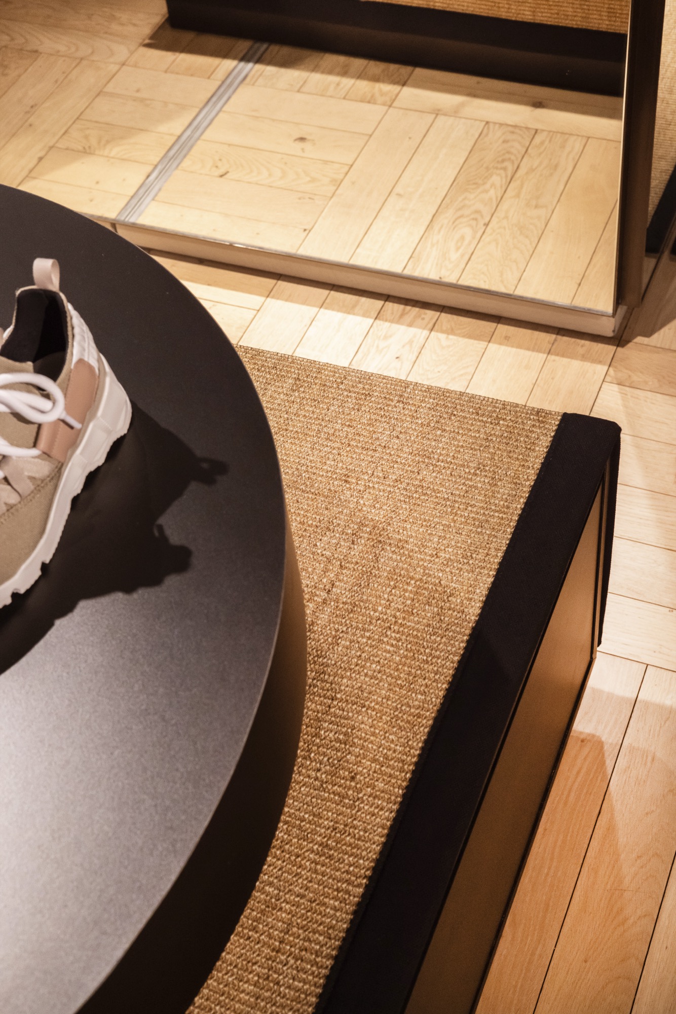 Sneakers Pierre Hardy présentées sur plinthes cylindriques devant le mur en raffia