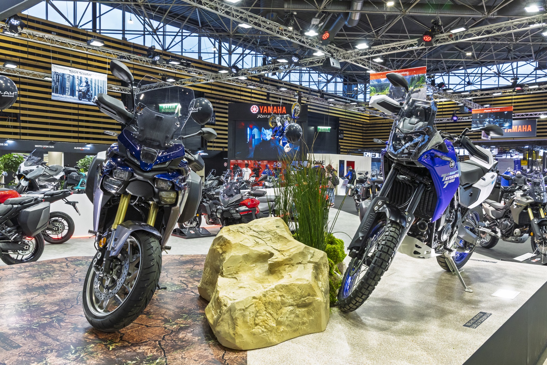 Yamaha Ténéré 700 présentée sur un décor de terrain au sein du stand