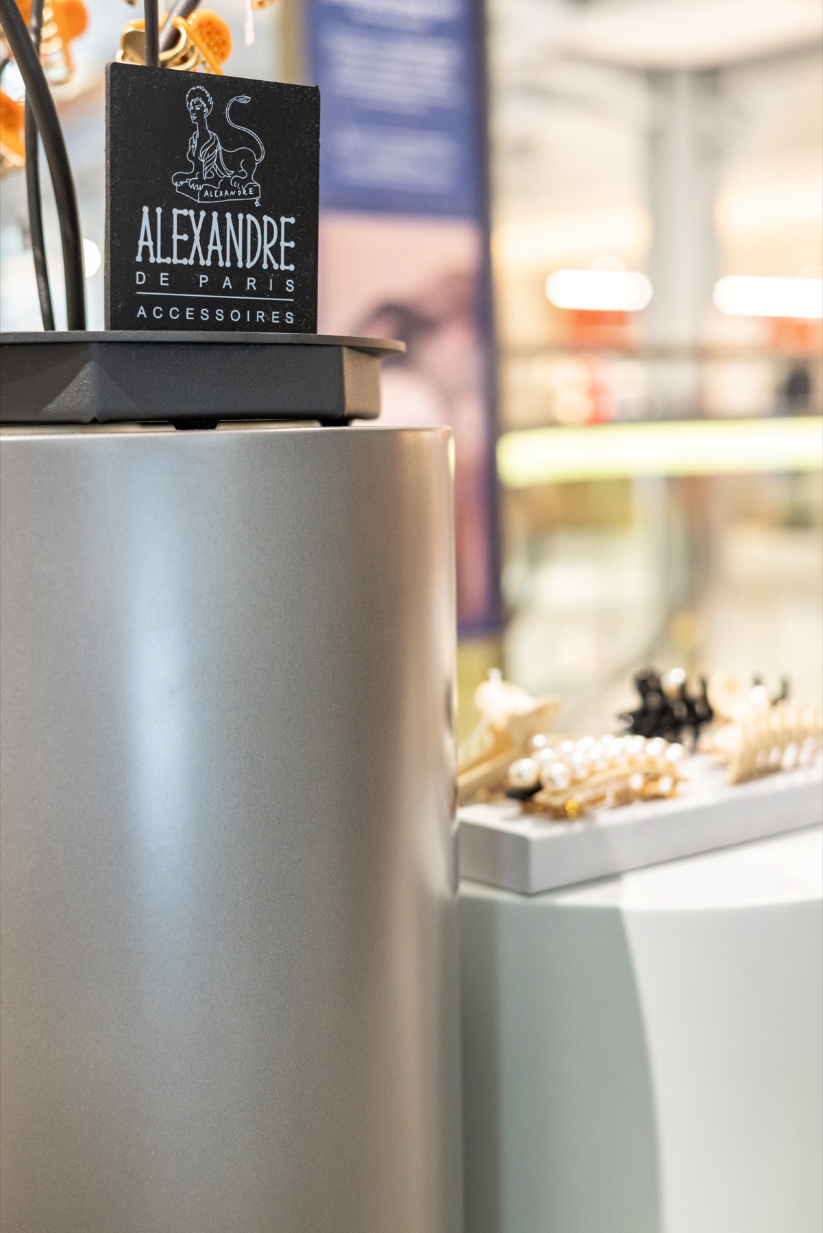 Signalétique Alexandre de Paris posée sur un podium métal du pop-up store