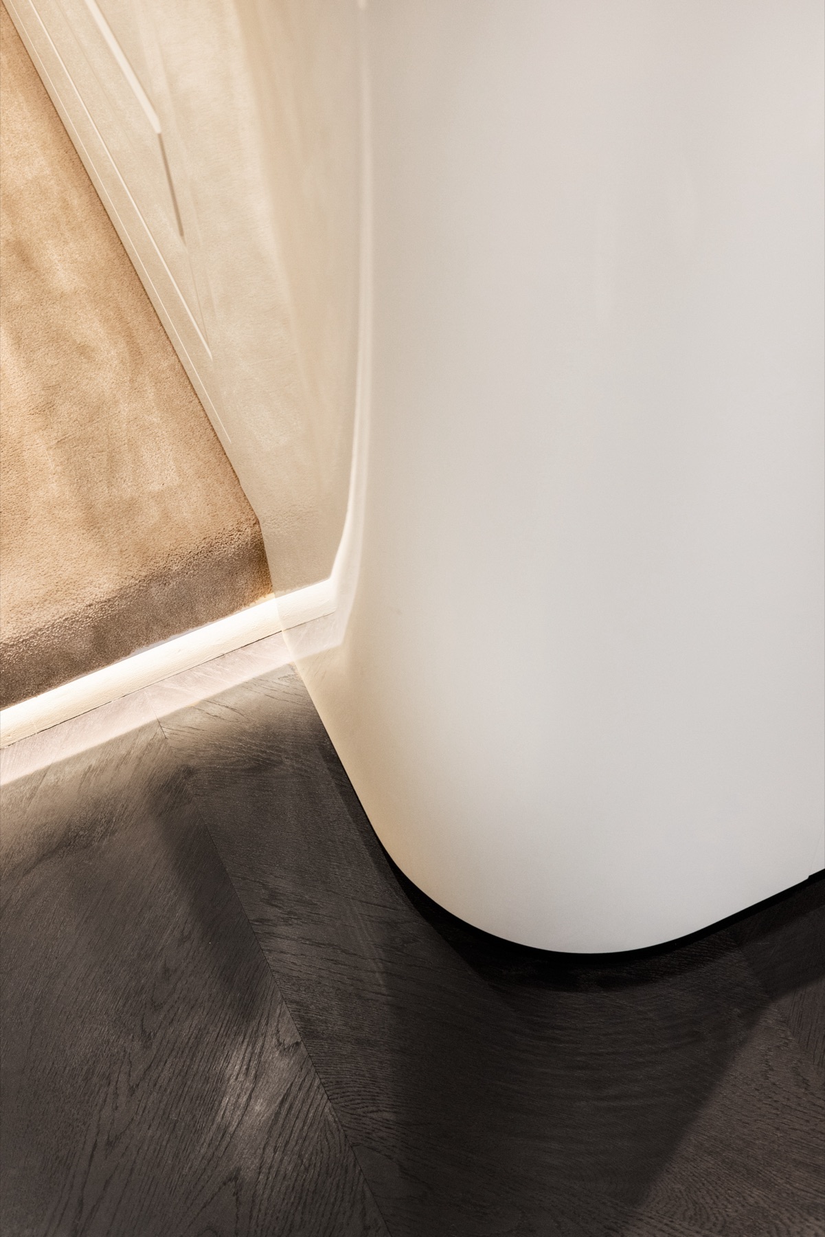 Détail de l'éclairage LED en pied de meuble sur parquet de chêne teinté