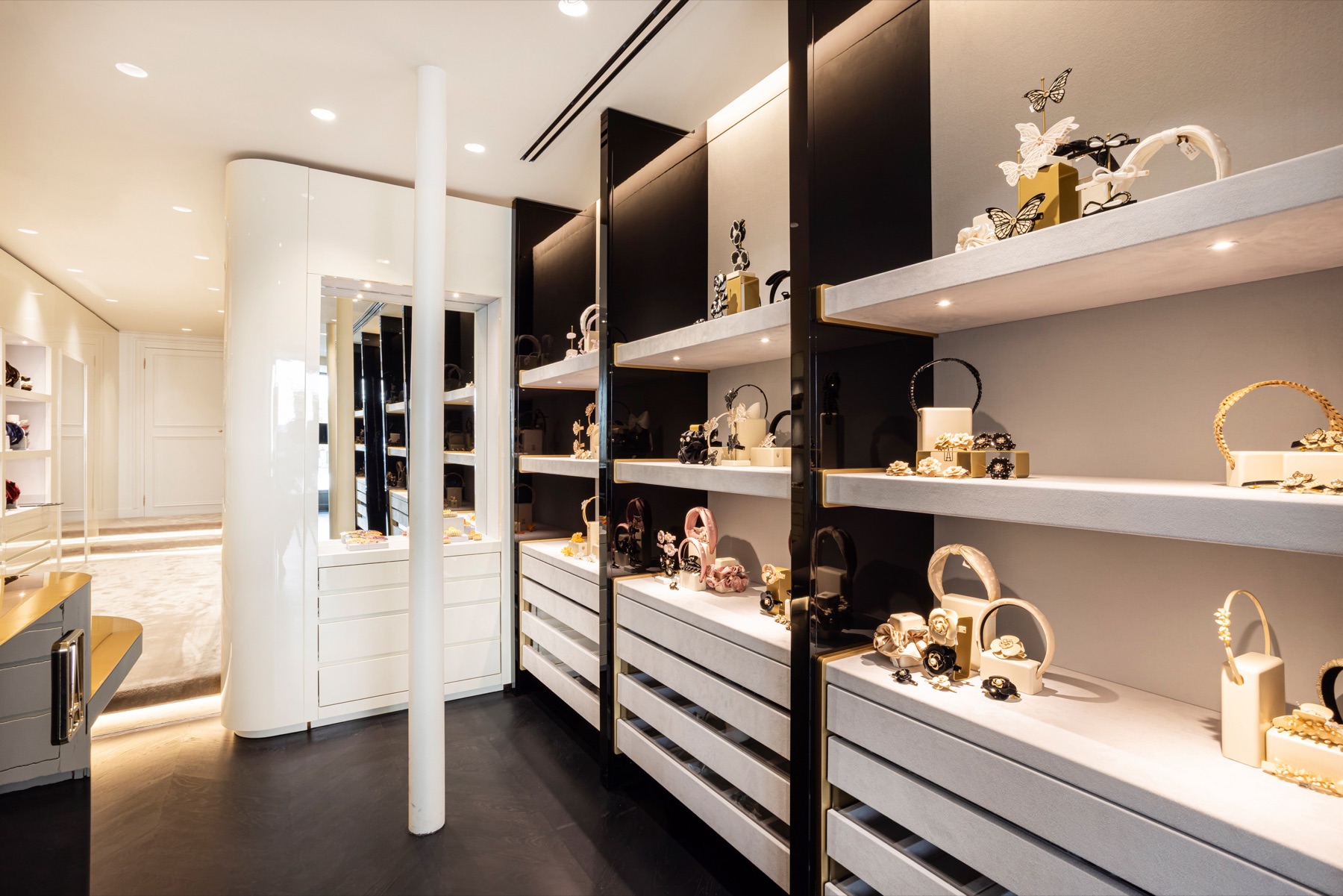 Étagères laquées noir et tablettes de pierre claire présentant les accessoires Alexandre de Paris