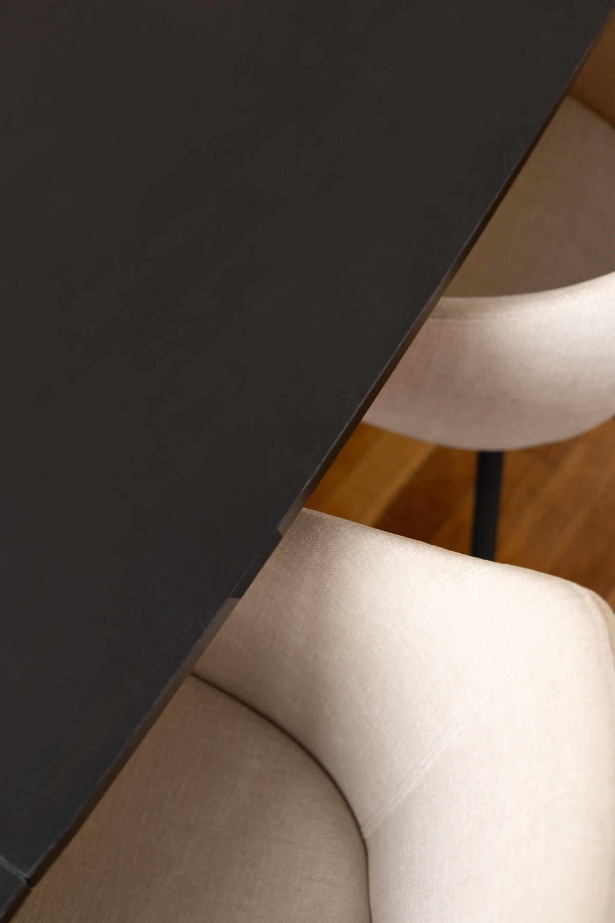 Détail du plateau noir de la table de réunion et d’une assise en tissu clair