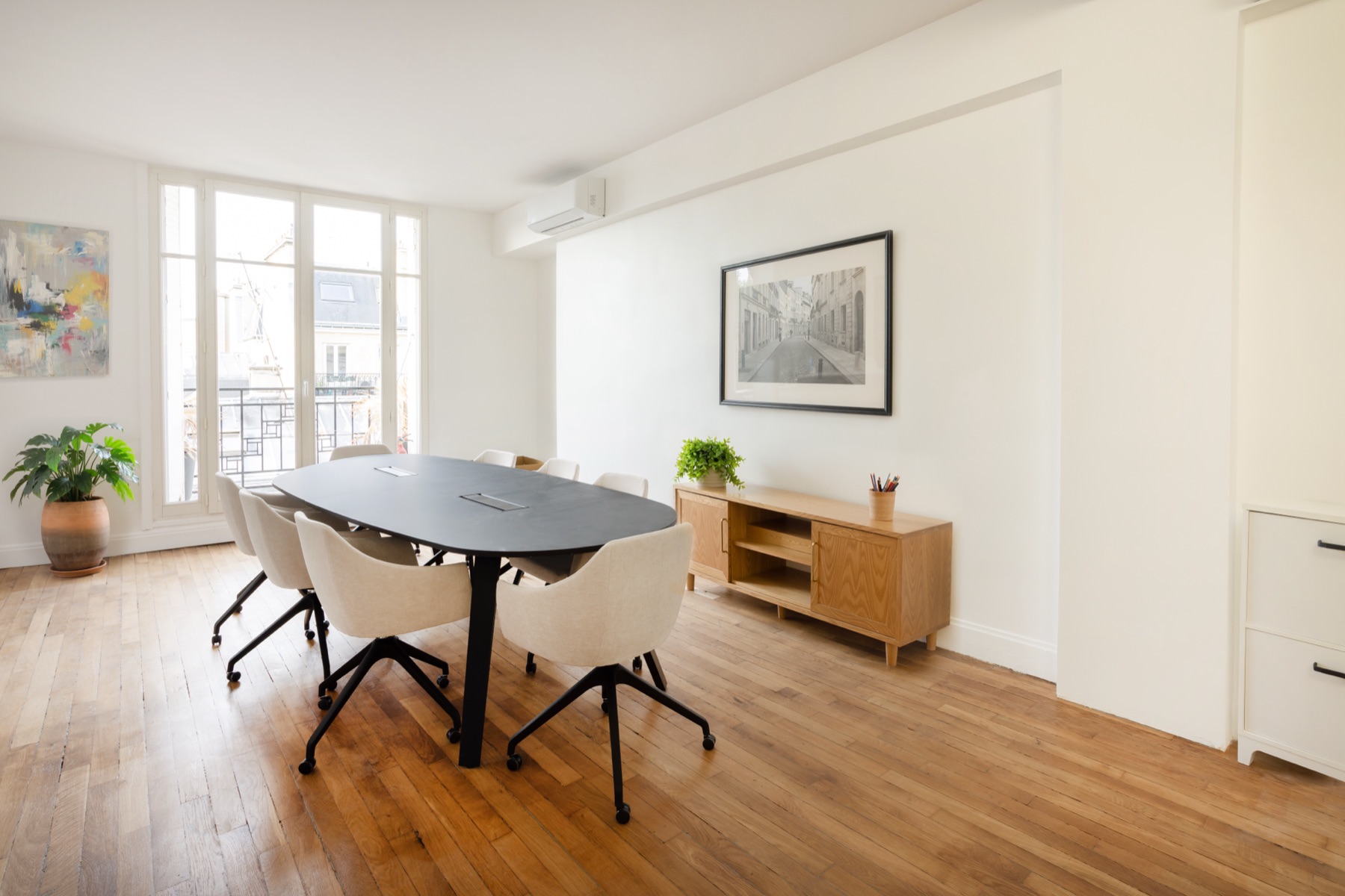 Salle de réunion des bureaux Act Beauty, table ovale noire, assises claires et parquet de chêne