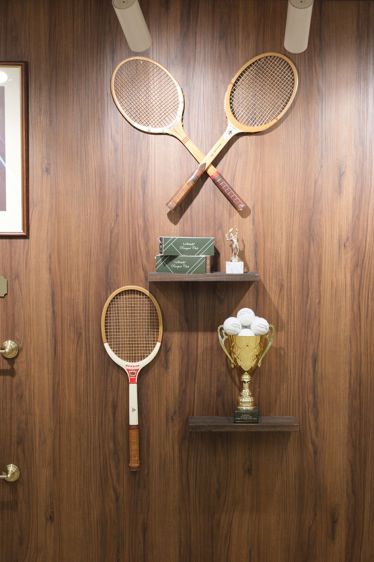 Raquettes de tennis en bois croisées et coupe dorée sur le mural La Boucle